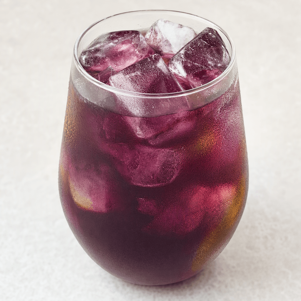 A translucent deep berry-purple tea is served over clear ice in a glass, with faint green-amber tones visible near the edges.