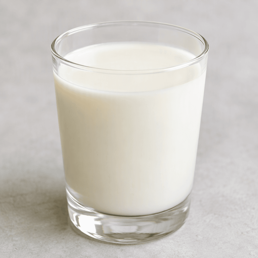 A smooth, opaque, pale ivory-white liquid with an even, slightly creamy appearance, served in a clear glass.