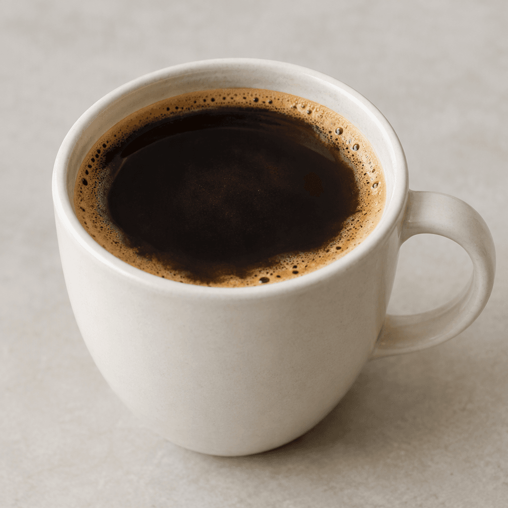 A clear, deep brown coffee with a thin tan crema floating on the surface, served in a plain ceramic cup.