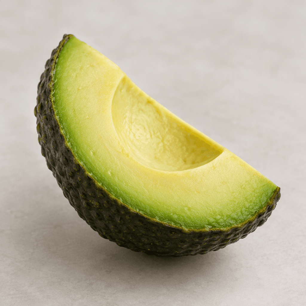 A quarter of an avocado with smooth pale green flesh, a darker green edge, and a curved strip of thick, textured dark green skin along the outside.
