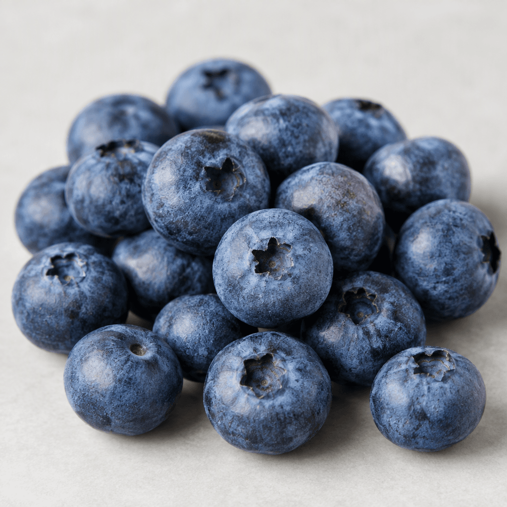 Small, round blueberries with deep blue to blue-purple skins, a soft powdery bloom, and tiny crown-shaped indentations are arranged loosely together.