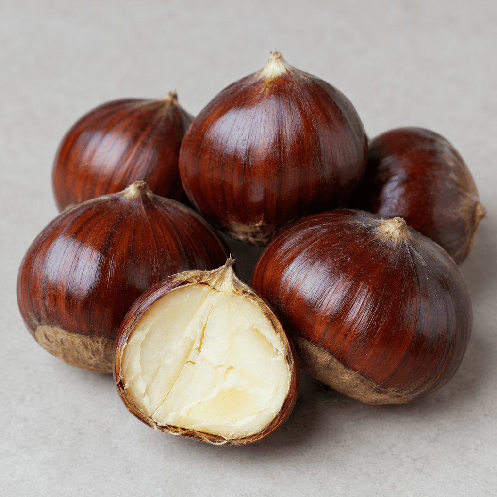 Glossy dark reddish-brown chestnuts with rounded, slightly flattened shells and pointed tips, shown whole alongside a cut-open chestnut revealing firm pale cream flesh.