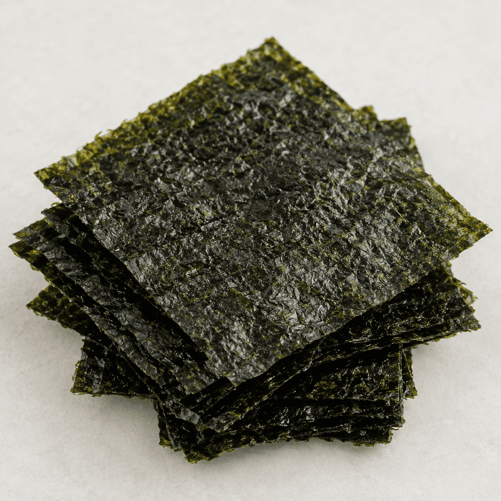 Thin, flat rectangular sheets of dried seaweed with a deep green to nearly black colour, a delicate crinkled surface, and a subtle dry sheen, arranged in a small overlapping stack.