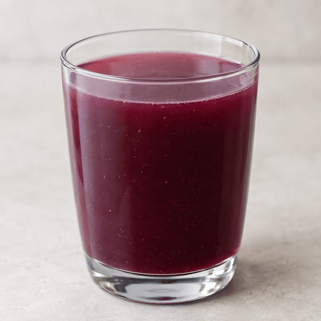 A deep burgundy-purple, slightly cloudy liquid fills a clear glass, with a smooth watery texture and a few tiny suspended particles.