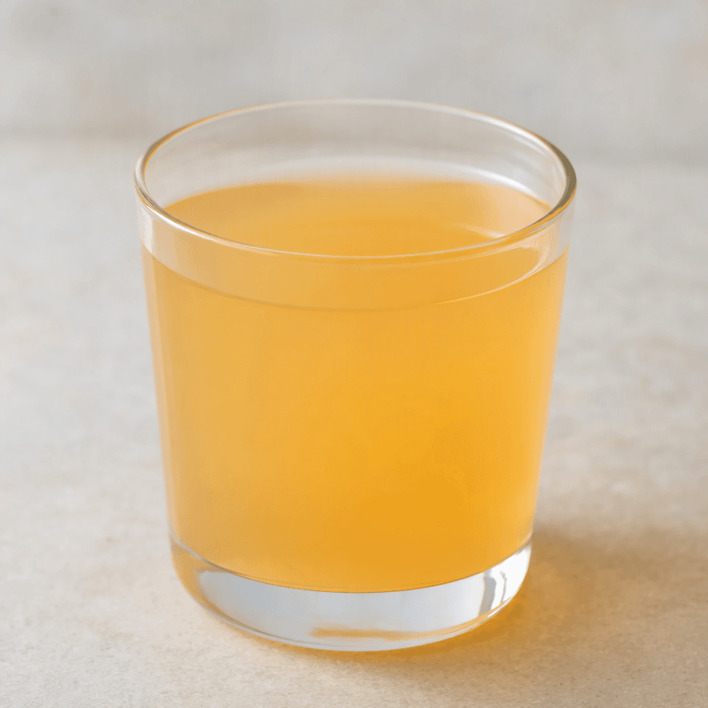 A small glass holds a smooth, translucent pale orange drink with no visible pieces or toppings.