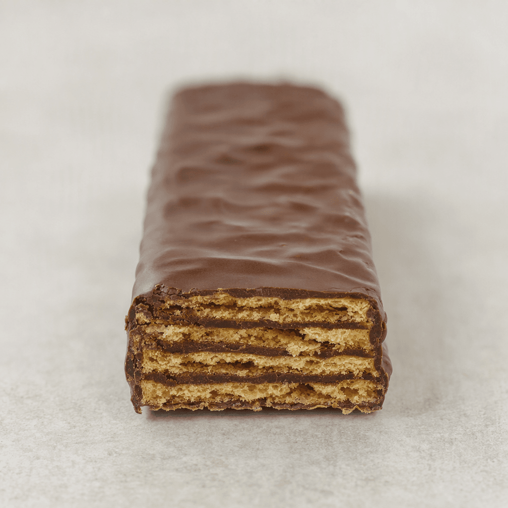 A long rectangular bar with a dark chocolate-brown coating, showing crisp thin wafer layers separated by darker cocoa cream at a broken end.