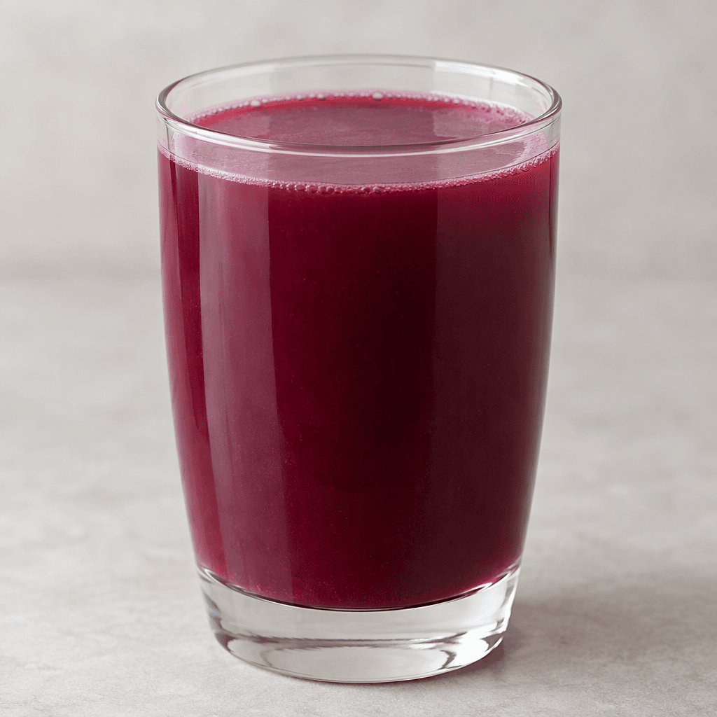 A deep burgundy-purple fruit drink with a slightly cloudy, even appearance, served in a clear glass.