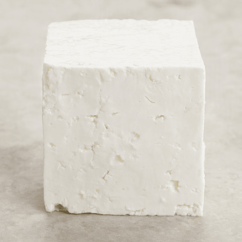 A firm, bright-white block of cheese with a smooth, slightly moist surface and clean-cut edges.
