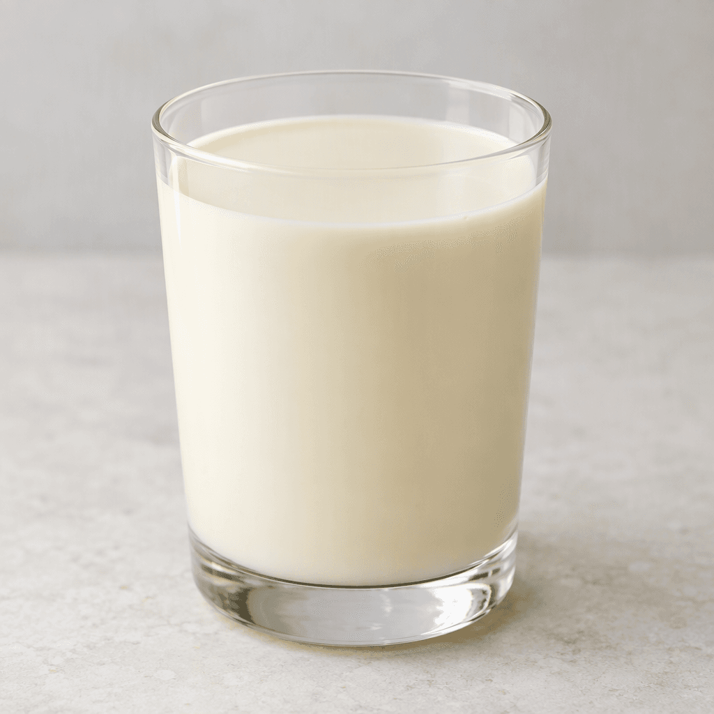 A smooth, opaque, pale cream-colored drink sits in a clear glass, with an even surface and no visible pieces or foam.