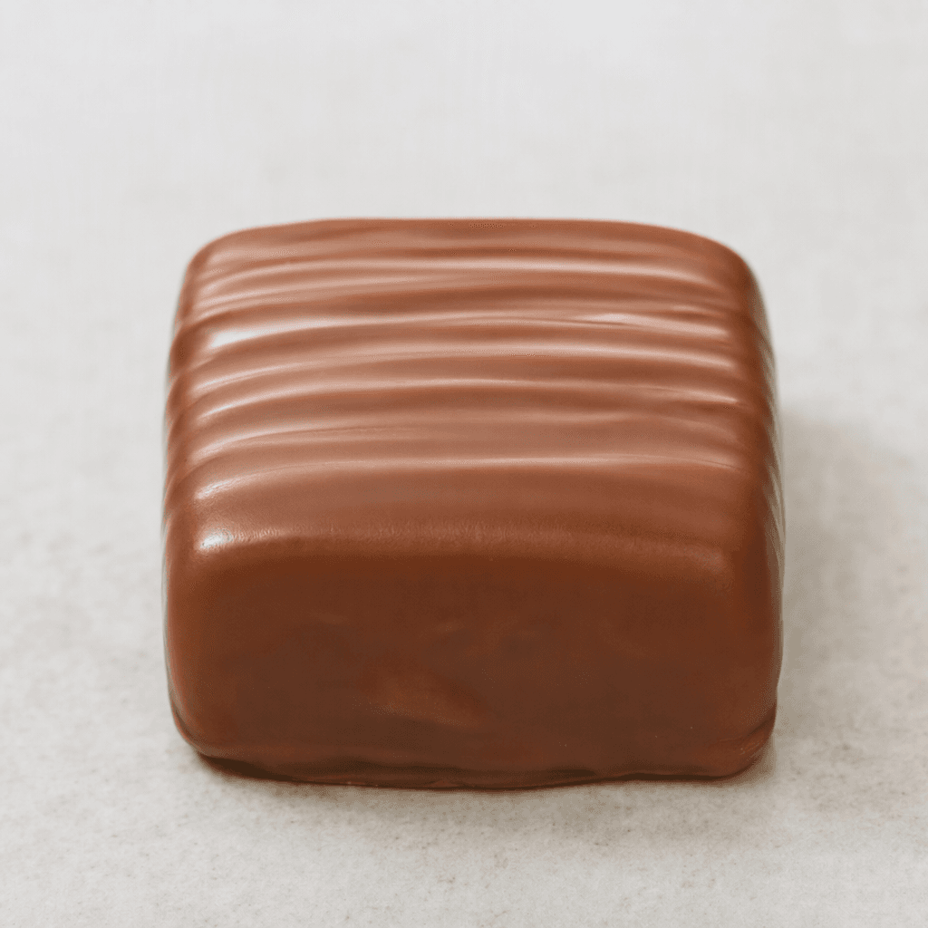 A short, rectangular bar with rounded corners, covered in a smooth brown chocolate coating and lightly ridged across the top.