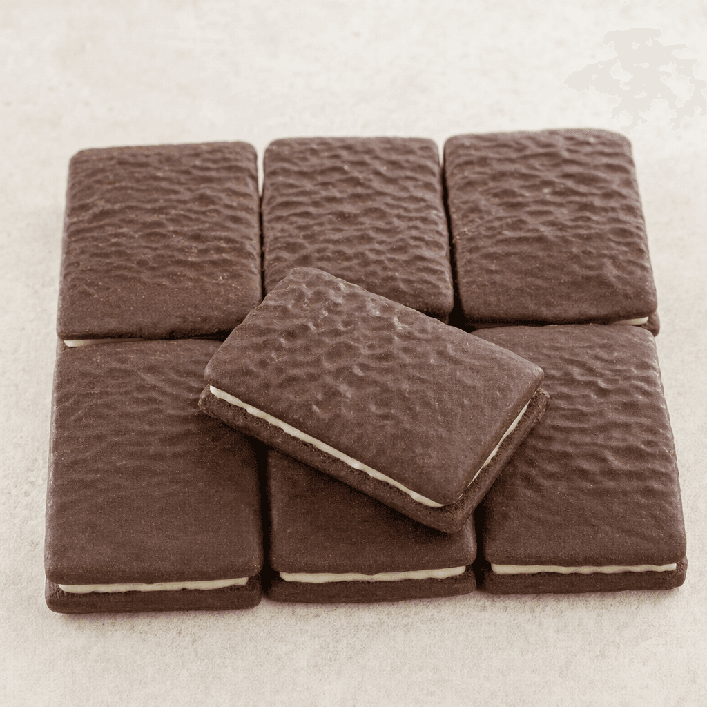 Small, rectangular, dark-chocolate-coated biscuits with a lightly textured surface and a pale filling visible between the layers, arranged side by side.