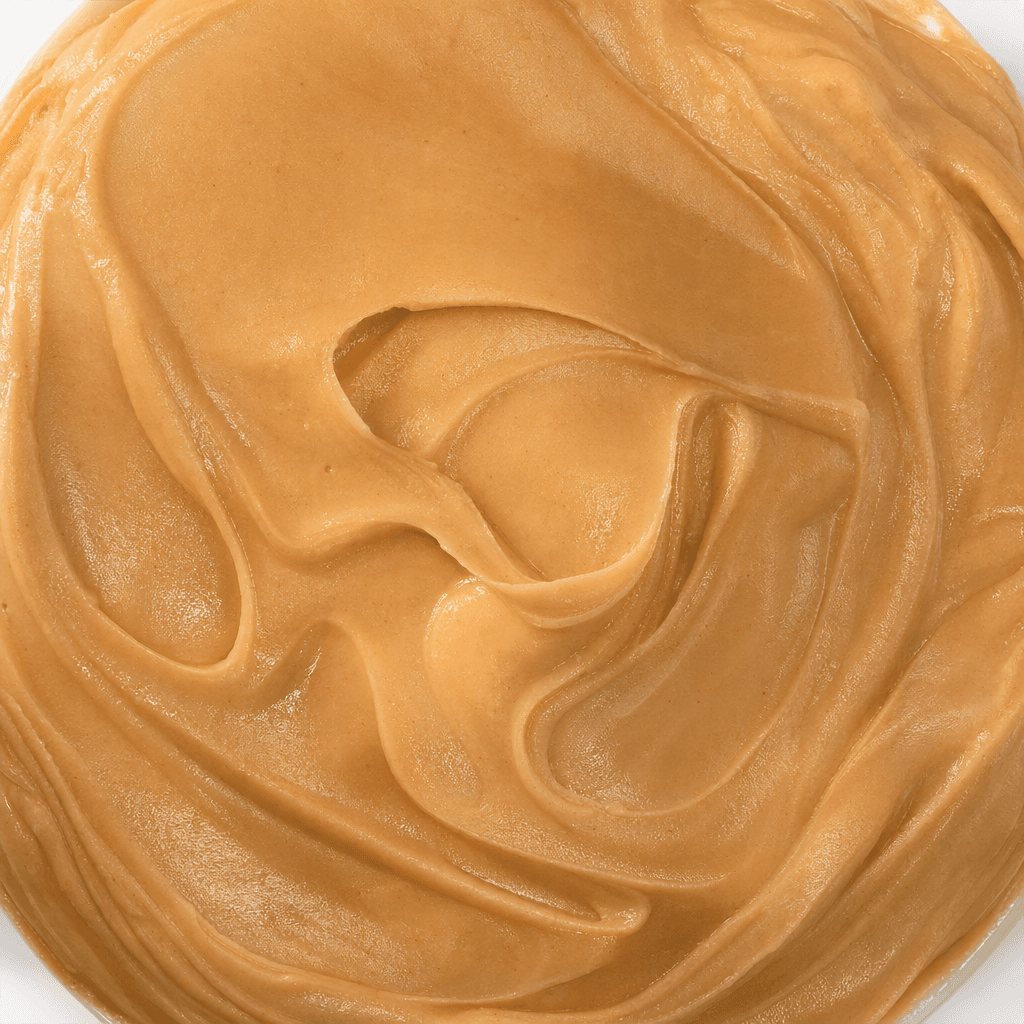 A thick, smooth, light-brown hazelnut spread with a creamy sheen, shown in a generous mound with soft ridges on its surface.