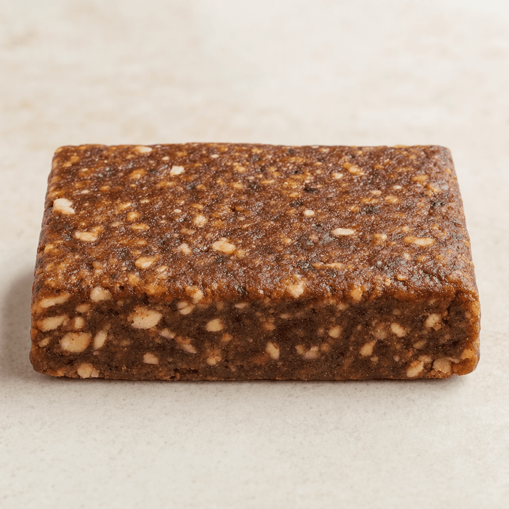 A compact, rectangular brown bar with a slightly uneven surface and small lighter-colored pieces visible throughout.