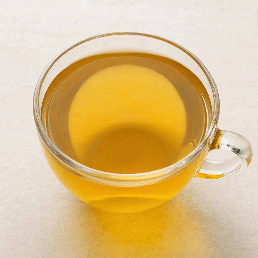 A clear, pale golden-amber herbal infusion sits in a cup, with a smooth surface and no visible leaves or other ingredients.
