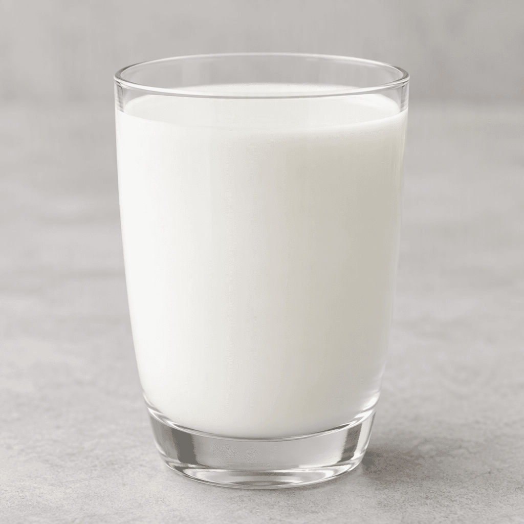 Opaque white, smooth milk fills a clear glass, with a clean, even surface.
