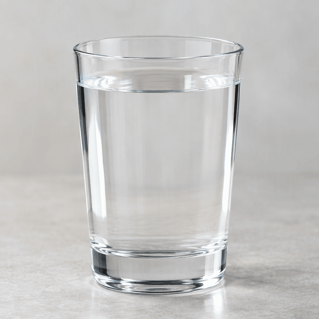 Clear, colorless water fills a transparent glass, with a smooth surface and no visible ingredients or sediment.