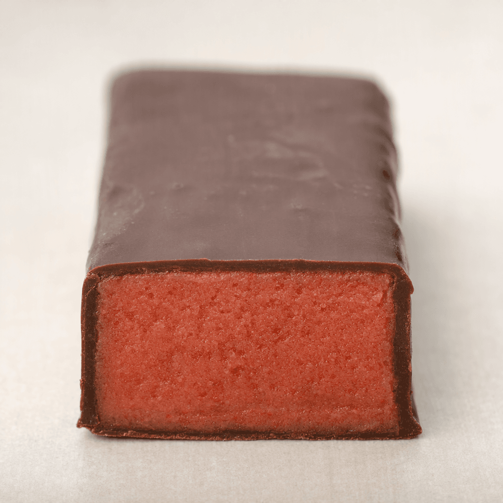 A rectangular strawberry-colored fruit bar with a smooth, dark chocolate coating and a pink-red center visible at a cut end.