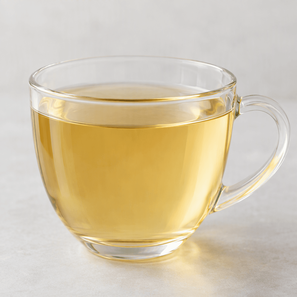 A pale golden, clear white-tea drink sits in a transparent cup, with no visible leaves or other ingredients.