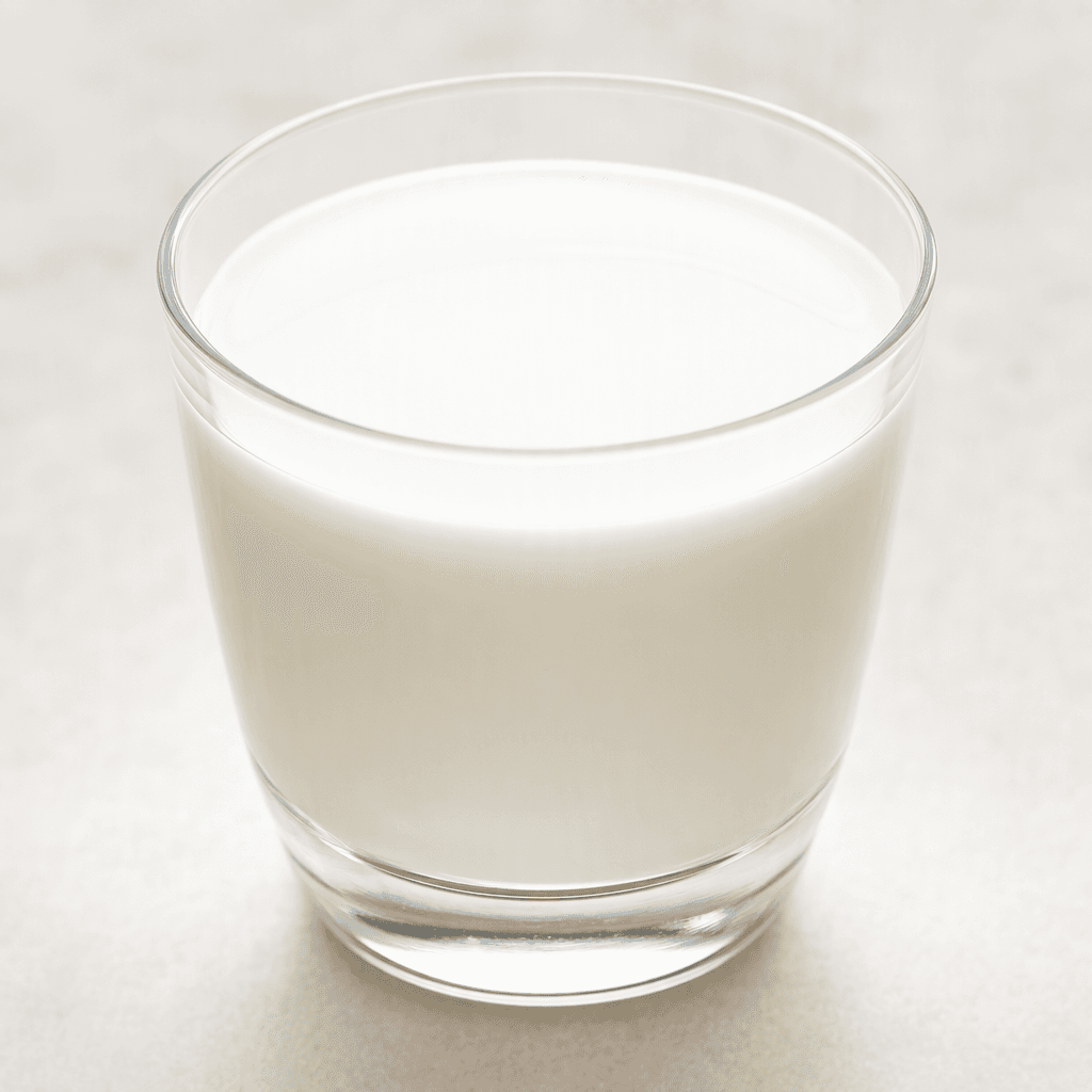 An opaque, creamy-white liquid with a smooth, uniform surface sits in a clear glass.