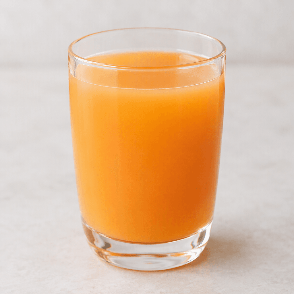 A translucent peach-orange drink is served in a clear glass, with an even colour and no visible pieces of fruit.