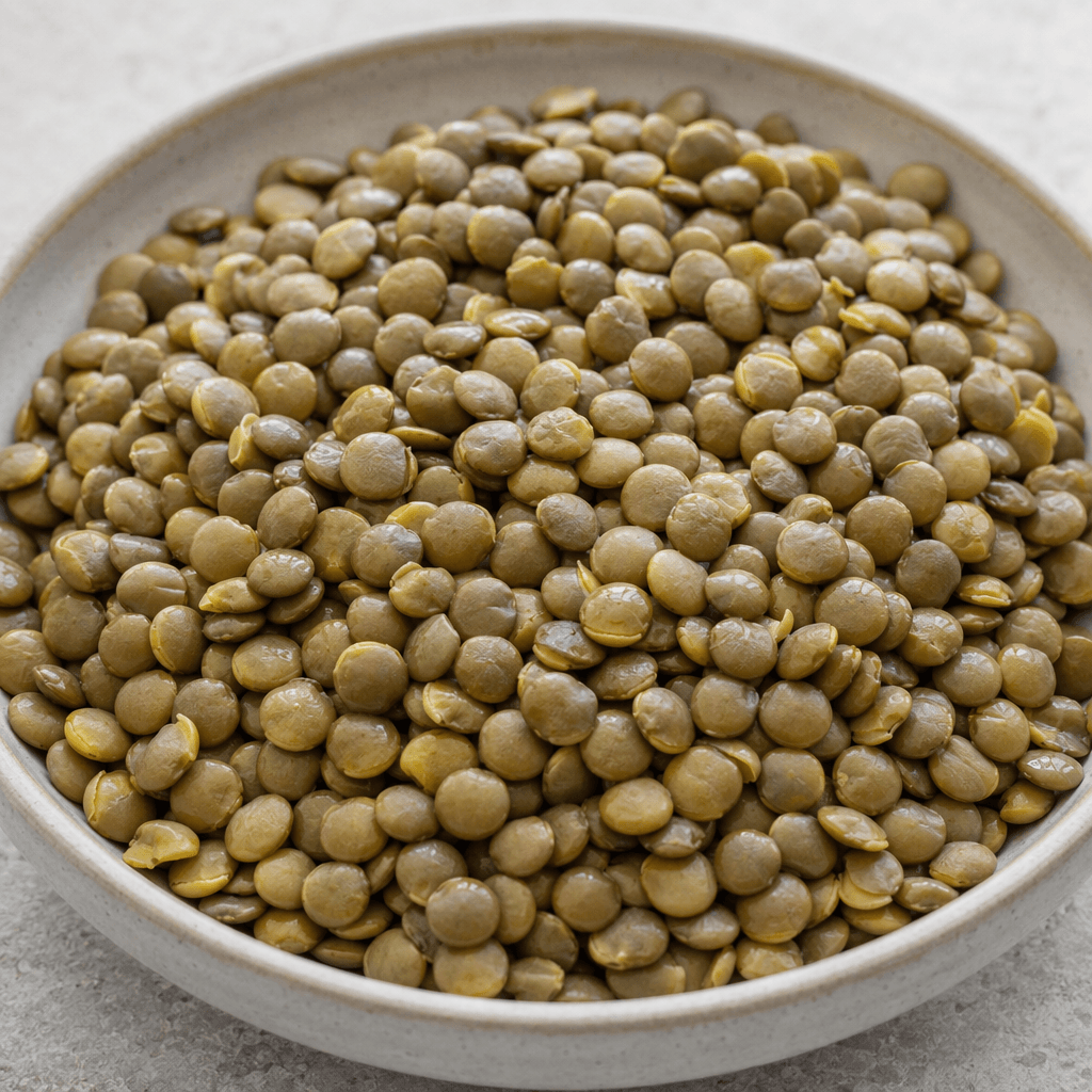 Zeytin yeşilinden kahverengiye çalan tonlarda, küçük, yuvarlak ve yassı mercimek taneleri yumuşak, hafif parlak yüzeyleri ve yer yer ayrılmış kabuklarıyla bir kâsede gevşekçe yığılmış halde görünür.