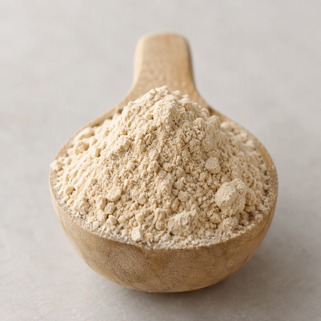 A mound of fine, pale beige powder with a soft, slightly clumpy texture sits in a small scoop.