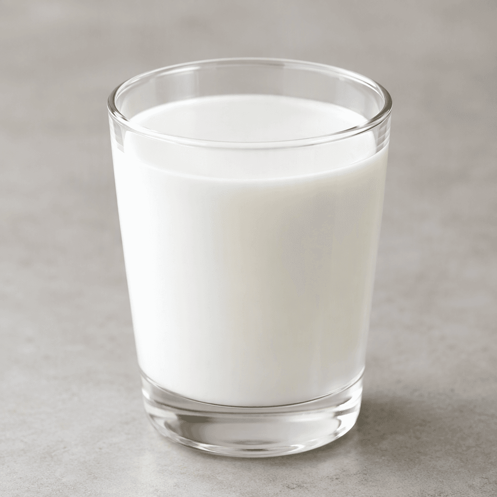 An opaque, bright-white, smooth liquid with a uniform, pourable appearance, shown in a clear glass with a level surface and a thin white sheen along the sides.