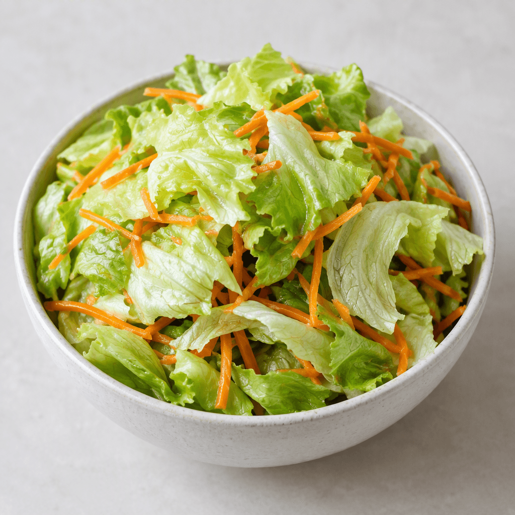 A bowl of crisp pale-green lettuce leaves mixed with thin orange carrot strips, loosely piled with the leafy and shredded textures clearly visible.