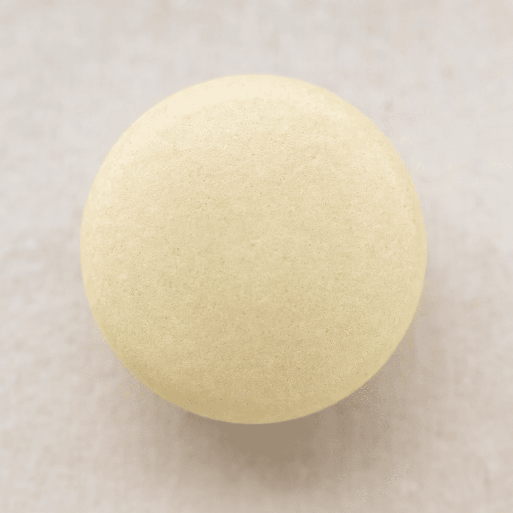 A small, round, pale cream tablet with a smooth, matte surface and gently rounded edges.