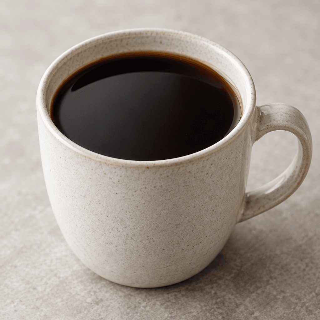 Dark brown, opaque coffee fills a cup, its surface smooth and unadorned.