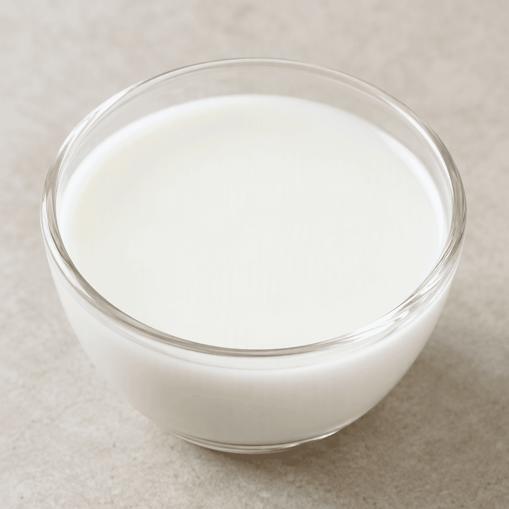 An opaque, milky-white liquid with a smooth, pourable texture, served in a clear glass or small bowl with an even surface.