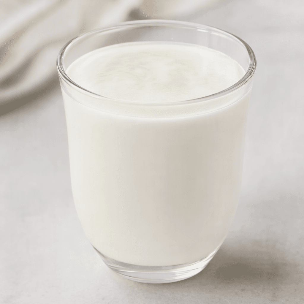Pürüzsüz ve hafif kıvamlı, opak beyaz kefir şeffaf bir bardakta servis ediliyor.