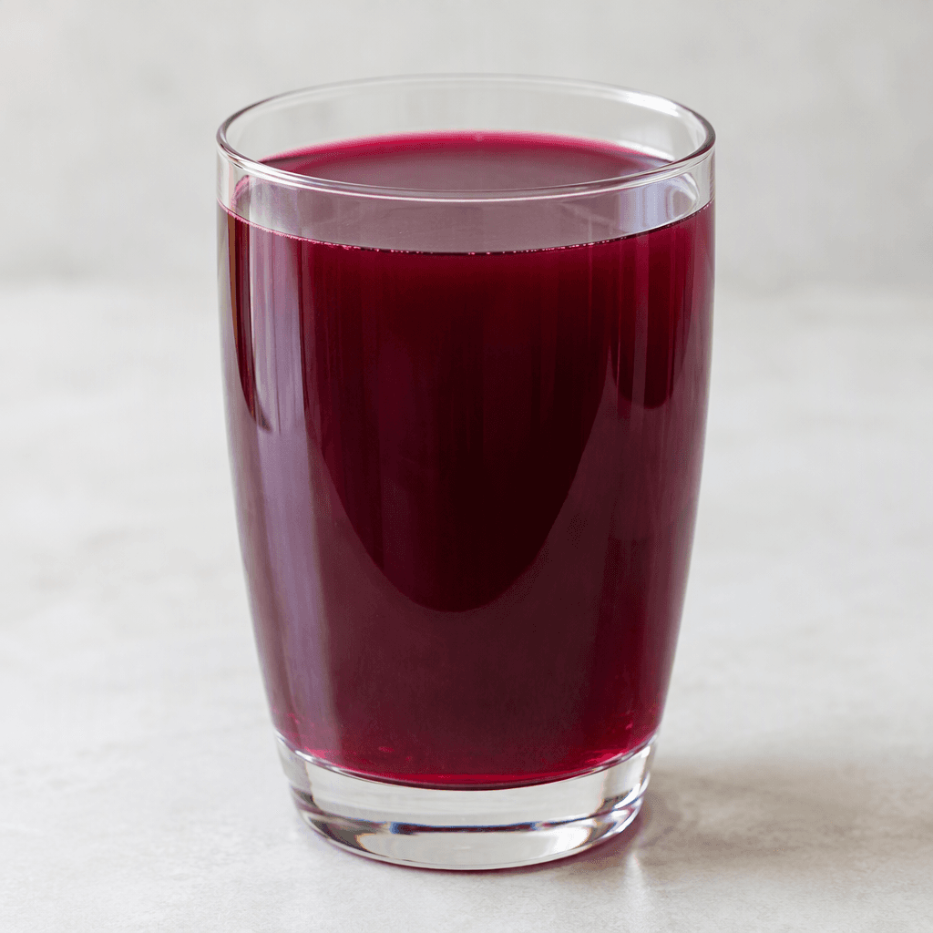 A translucent deep purple-red drink with a smooth surface fills a clear drinking glass.