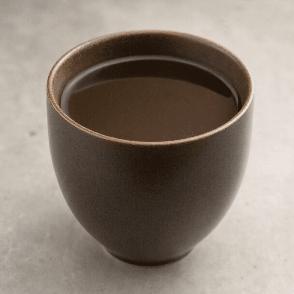 A deep brown, nearly opaque drink with a smooth surface, served in a plain cup.