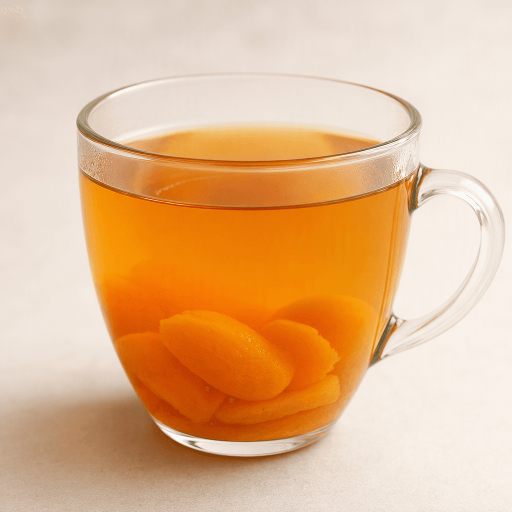 A clear glass cup holds translucent amber-orange apricot herbal tea, with a few soft apricot pieces visible near the bottom.