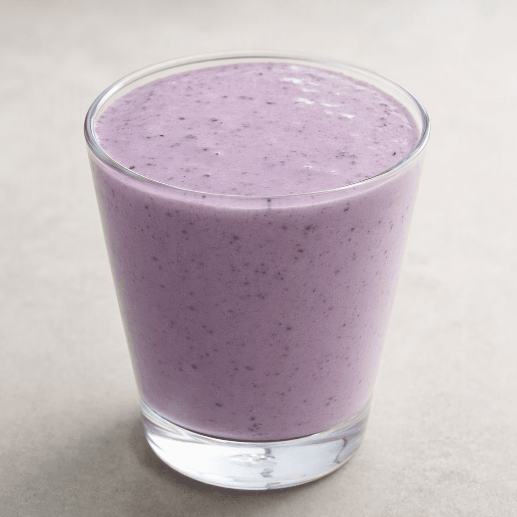 A thick, smooth, pale purple kefir with a few tiny dark berry flecks, served in a clear glass.