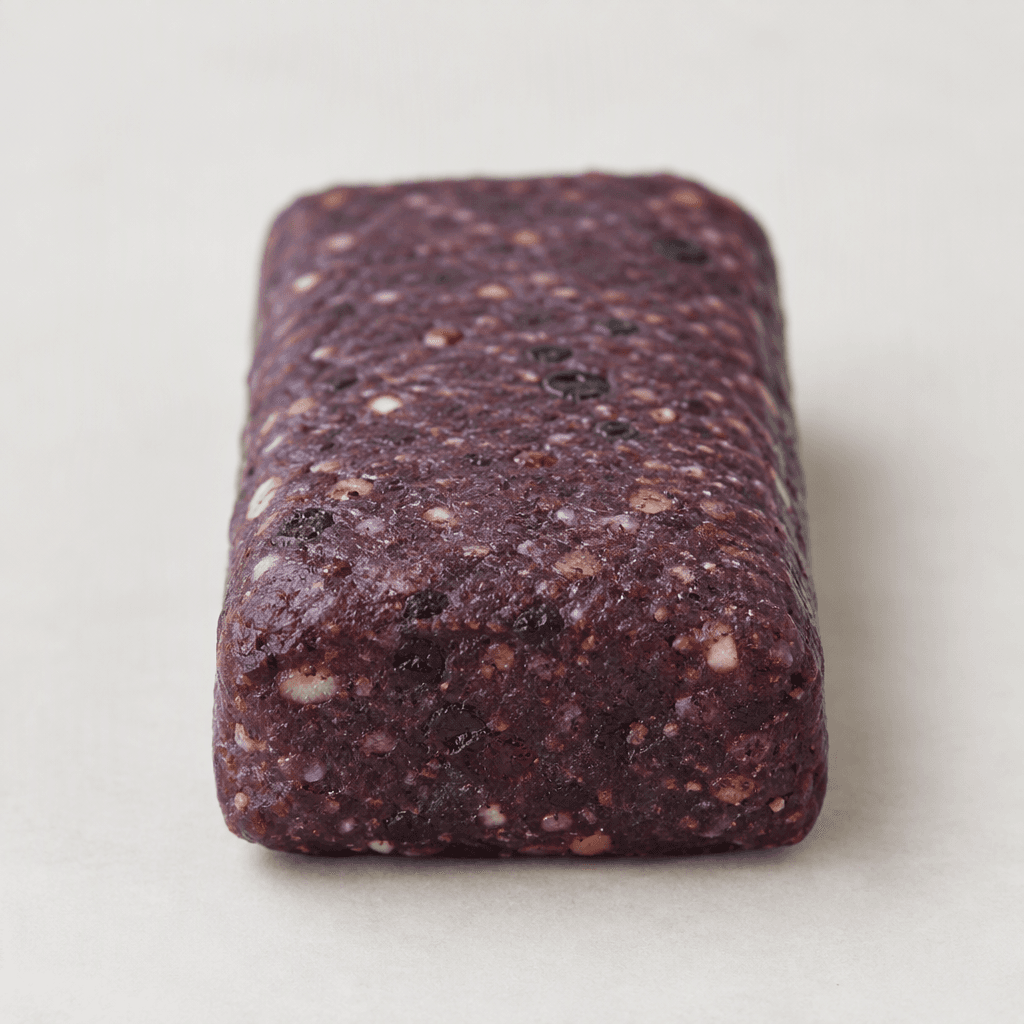 A compact, rectangular protein bar with a deep purple, slightly textured surface and softly rounded edges.
