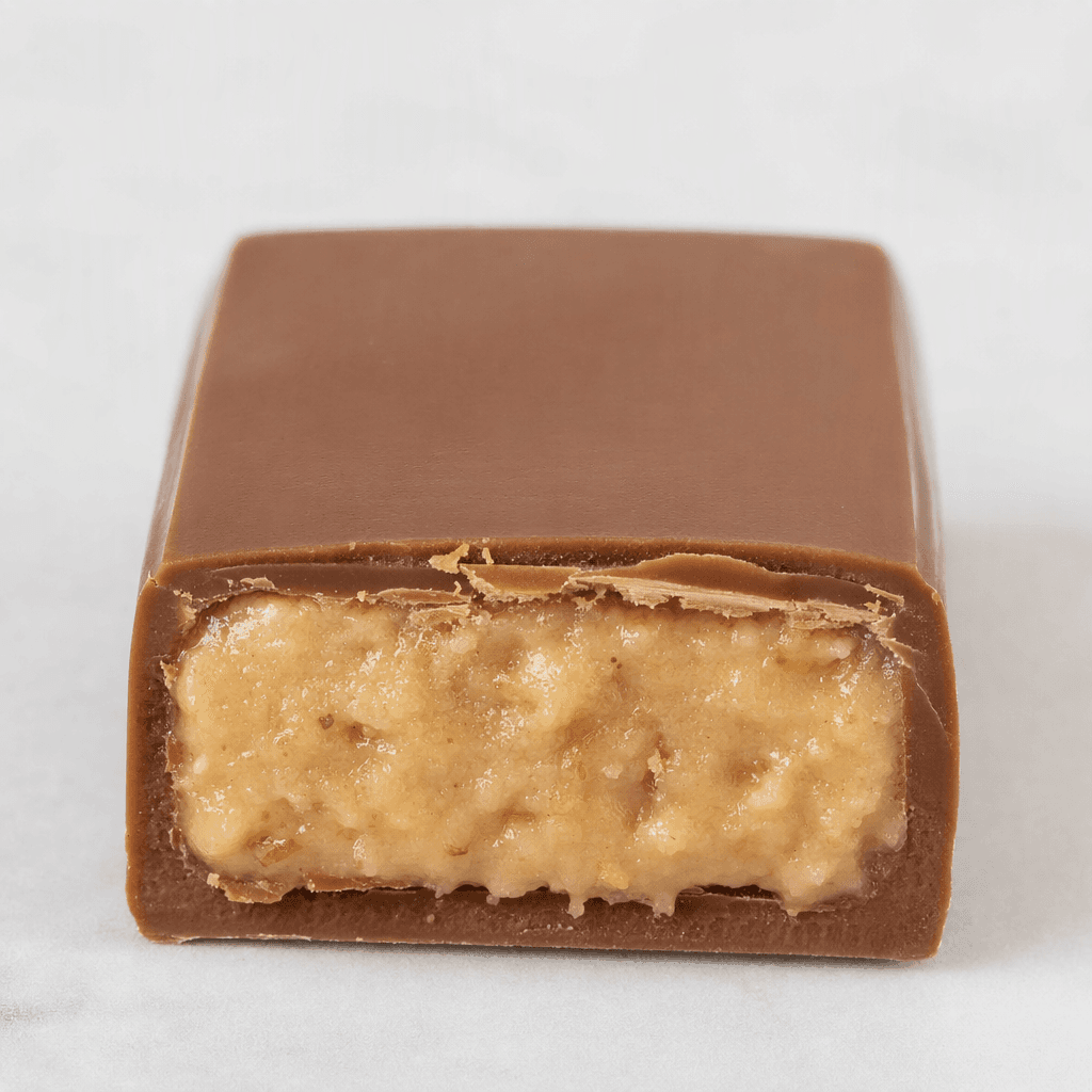 A small, rectangular milk-chocolate bar with a smooth, glossy brown shell and a pale, creamy hazelnut filling visible at a broken end.