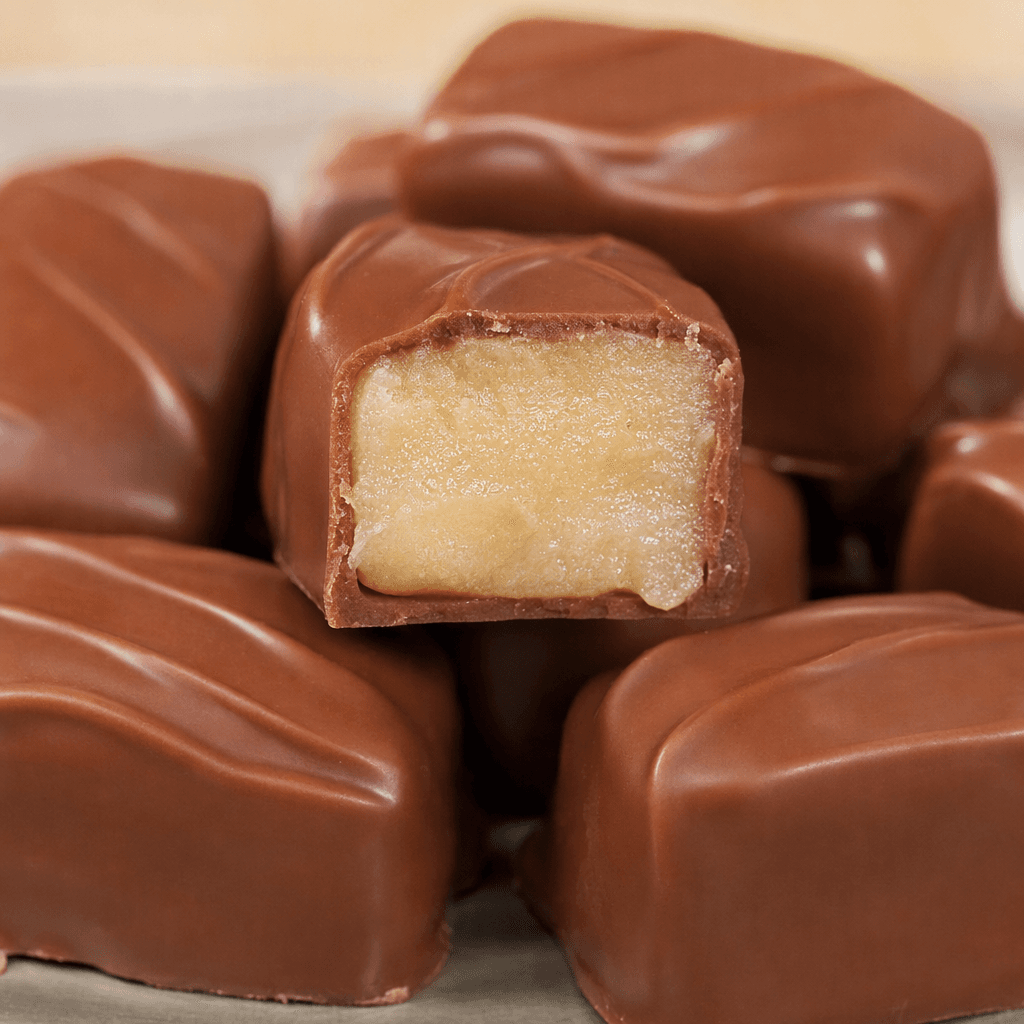 Small, bite-sized rectangular chocolates with smooth, glossy milk-chocolate shells and a pale, creamy praline center visible where one is cut open.