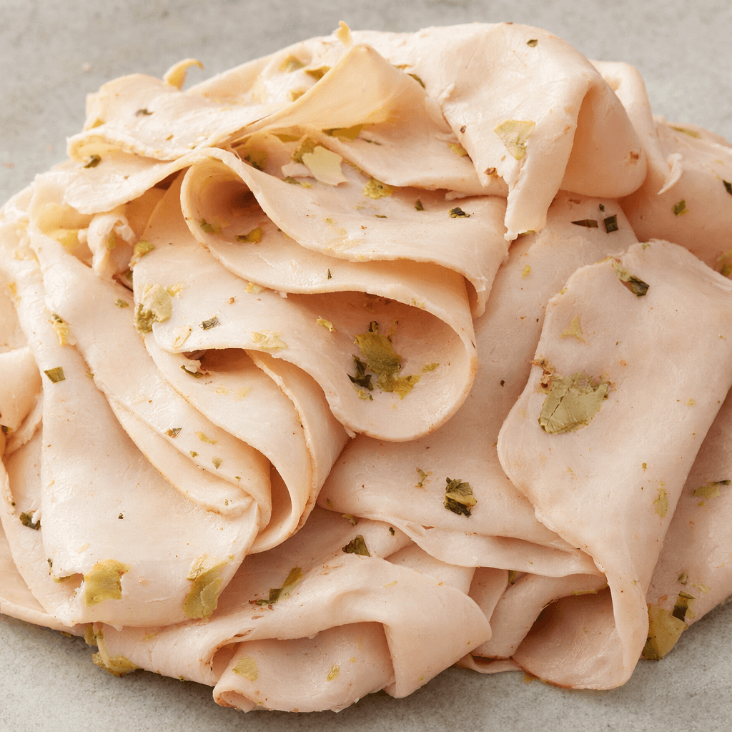 Thin, pale pink slices of turkey breast are arranged in a loose stack, with small green and cream-colored pieces of artichoke visible throughout.