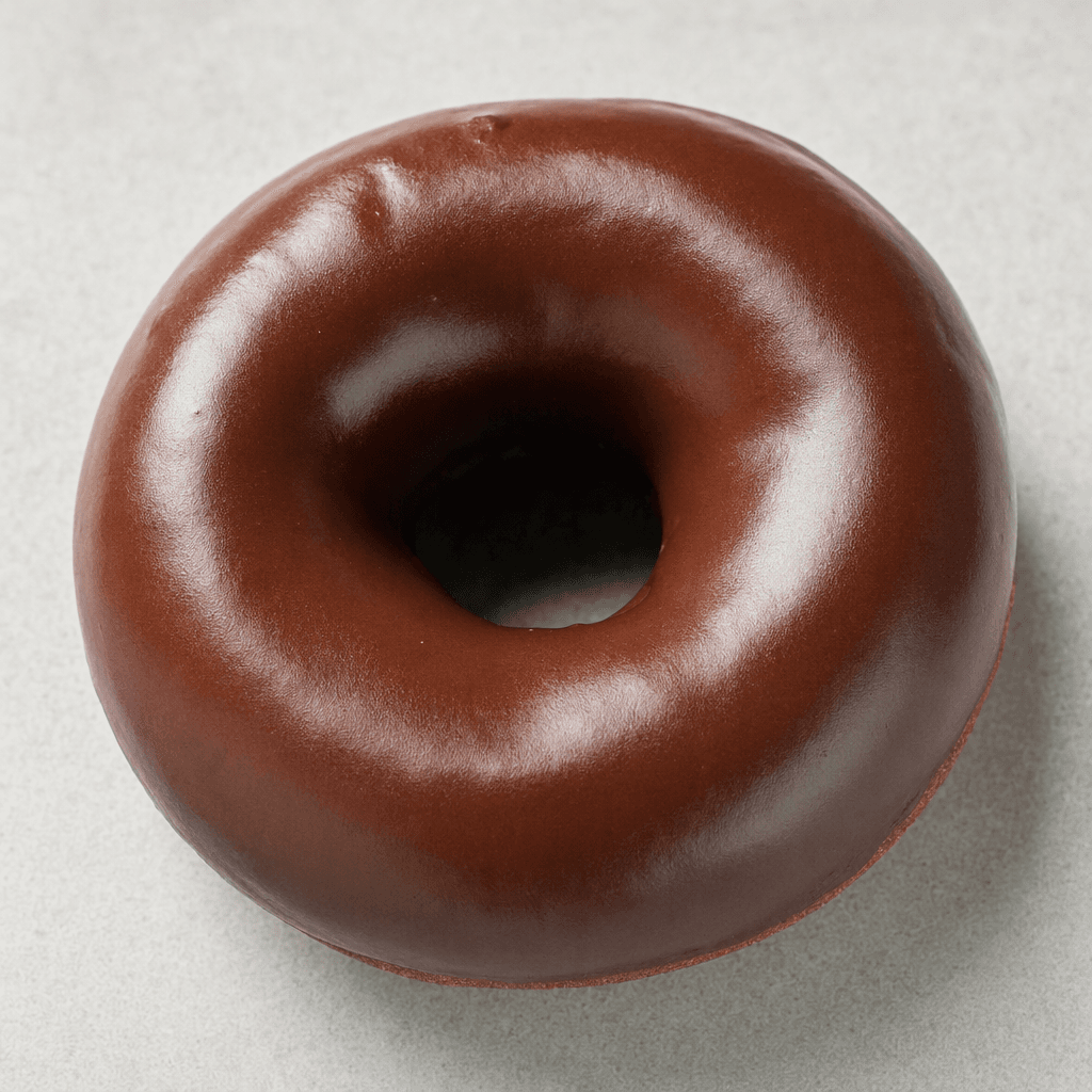 A ring-shaped doughnut with a smooth, glossy dark-brown chocolate coating, shown whole against a plain surface.
