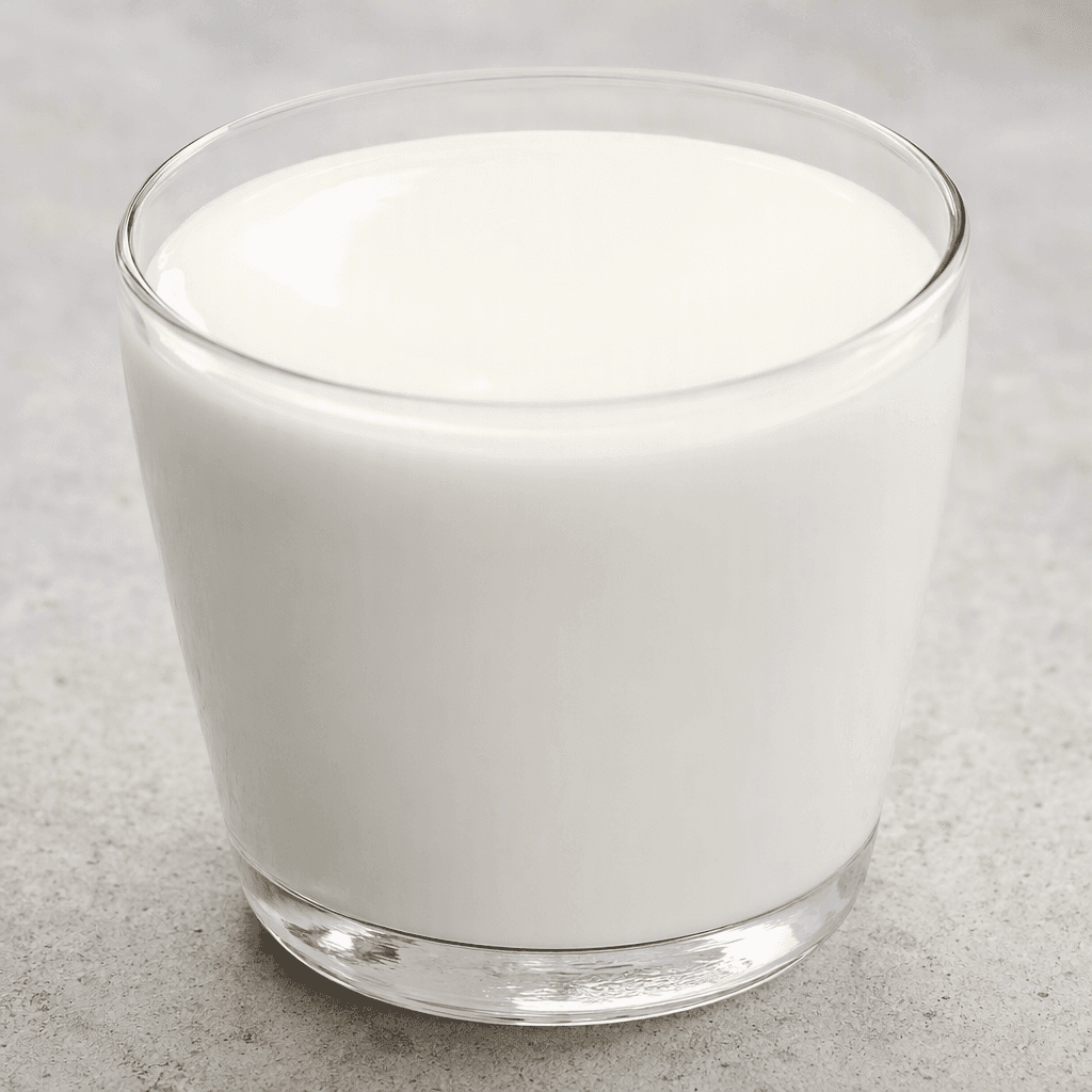 A smooth, opaque white liquid with a slightly creamy appearance, poured into a clear glass and forming a clean, glossy surface.