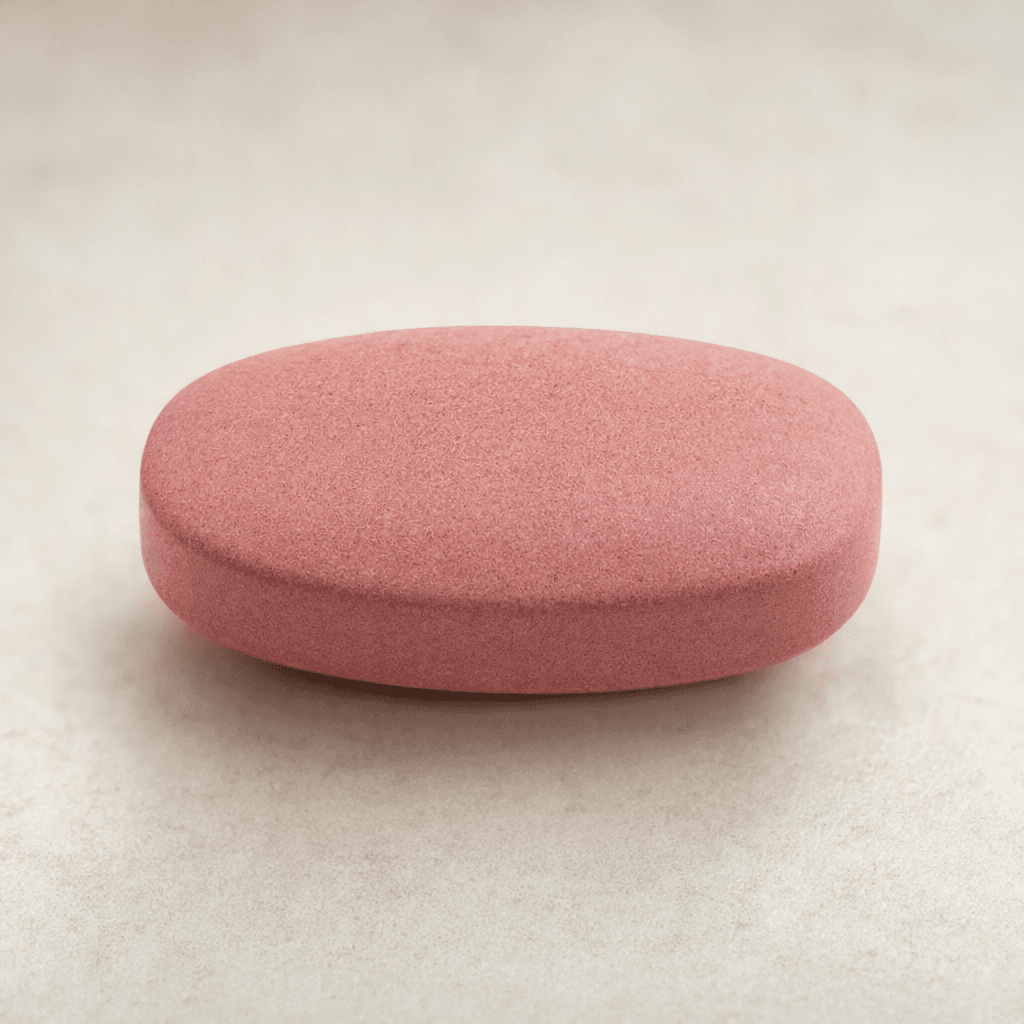 A smooth, compact, oval tablet with a muted pink surface and gently rounded edges.