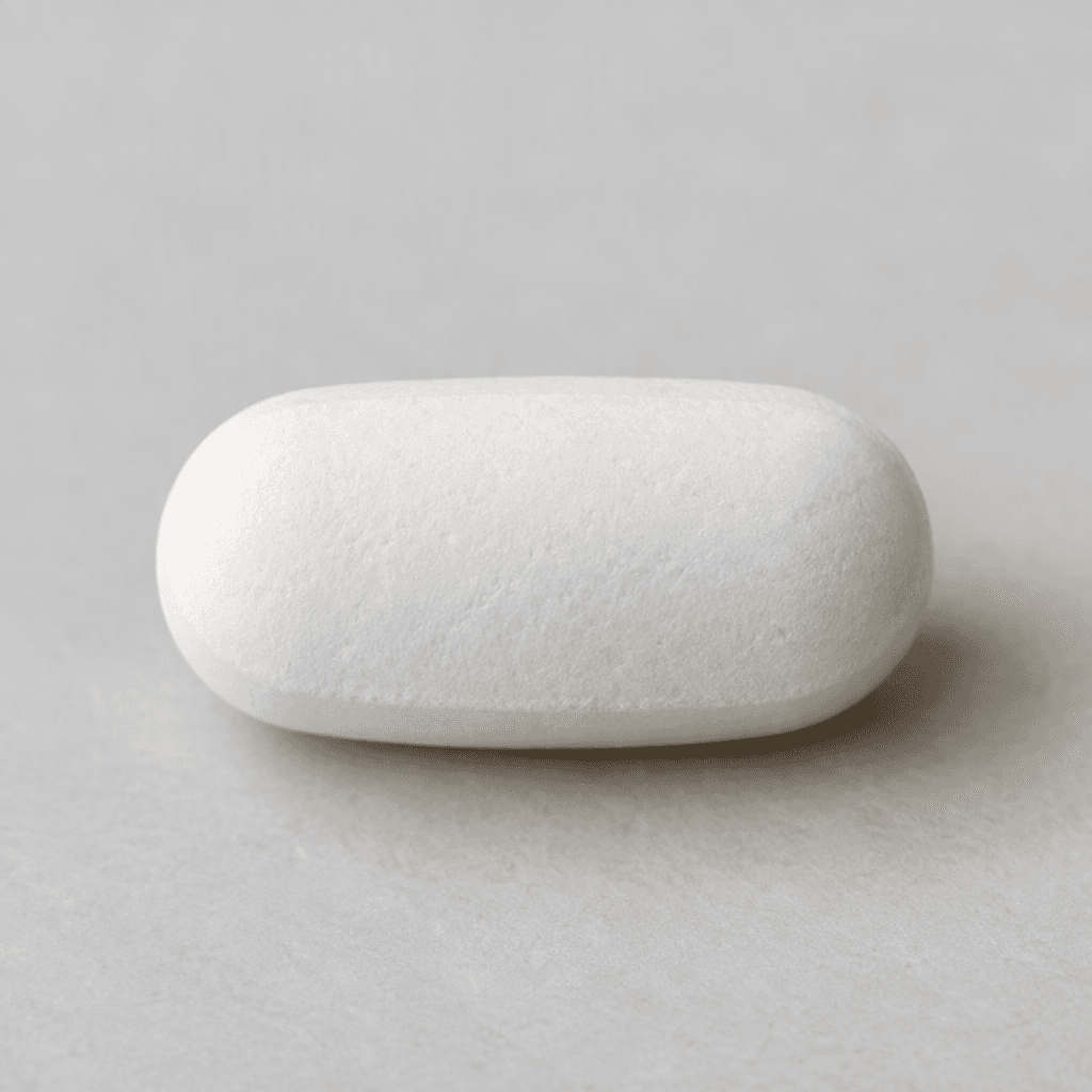 A pale white, smooth, oblong tablet with rounded ends, shown on a plain surface.
