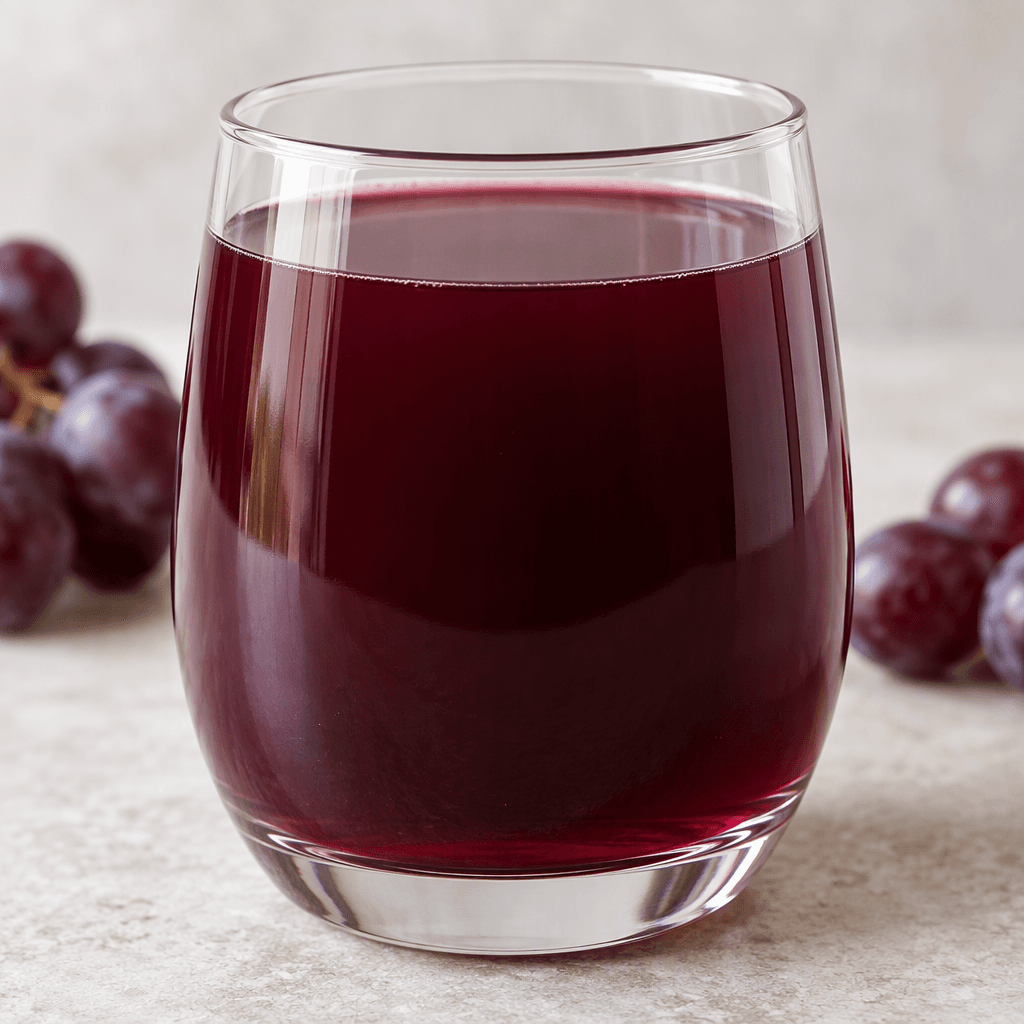 Deep purple-red grape juice fills a clear glass, with a smooth, translucent surface and a faint darker band near the bottom.
