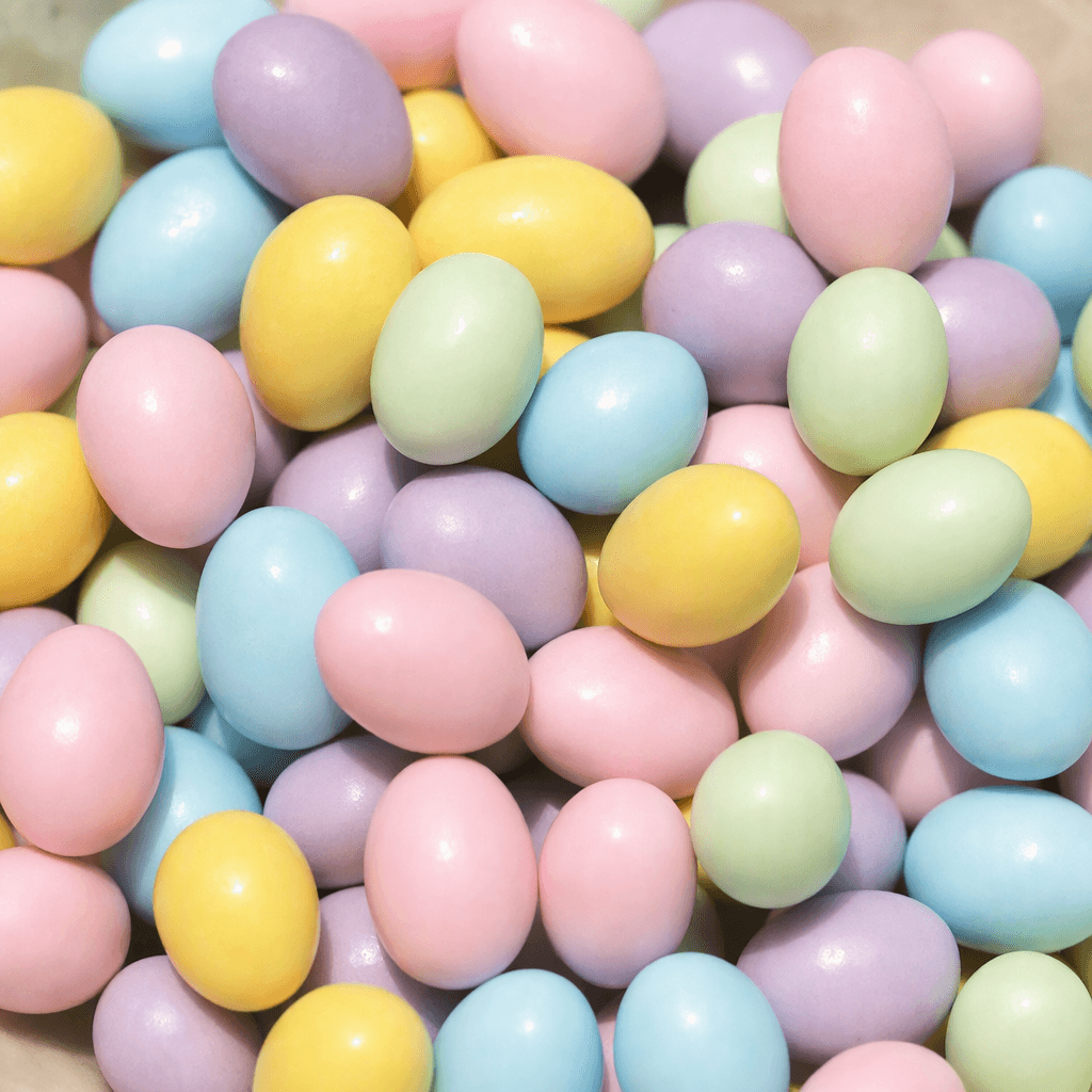 Small, smooth egg-shaped chocolates with a glossy candy coating in assorted pastel colors, shown together.
