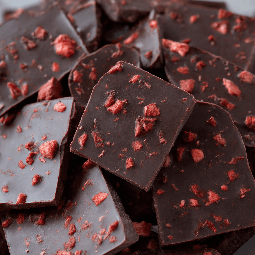 Dark brown chocolate pieces with small red strawberry fragments visible across their surface.