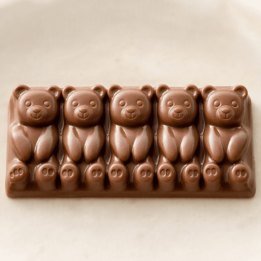 A glossy milk-chocolate bar molded into a row of small bear-shaped pieces, with rounded ears and raised facial details.