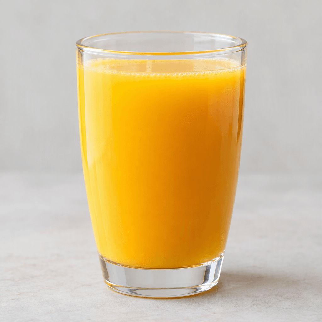 Opaque golden-orange juice with a smooth, even texture fills a clear drinking glass.