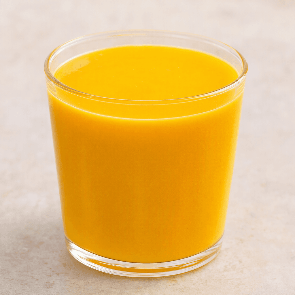 A smooth, opaque golden-orange drink fills a clear glass, with an even surface and no visible pieces.